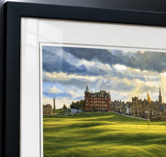Close-up photograph of a framed St Andrews fine-art print, showing the artwork, white mount and black frame